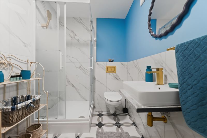Top 6: bathroom with a glass shower, marble-look tiles, a blue wall and a gold tap