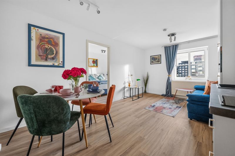 Top 6: open living and dining area with a round dining table, a blue sofa and a kitchen counter