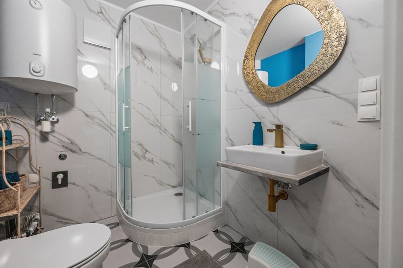 Top 7: bathroom with a round glass shower, marble-look tiles and a gold-framed mirror