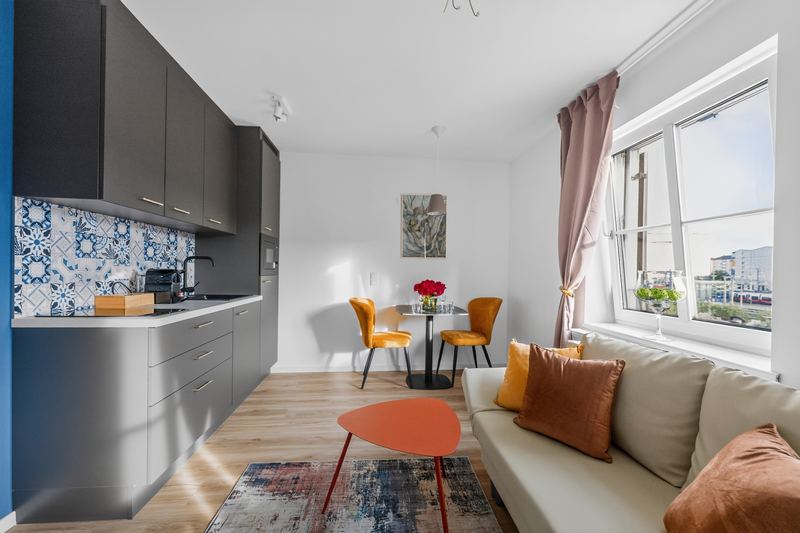 Top 7: kitchen counter with grey cabinets, a table for two with orange chairs and a sofa by the window